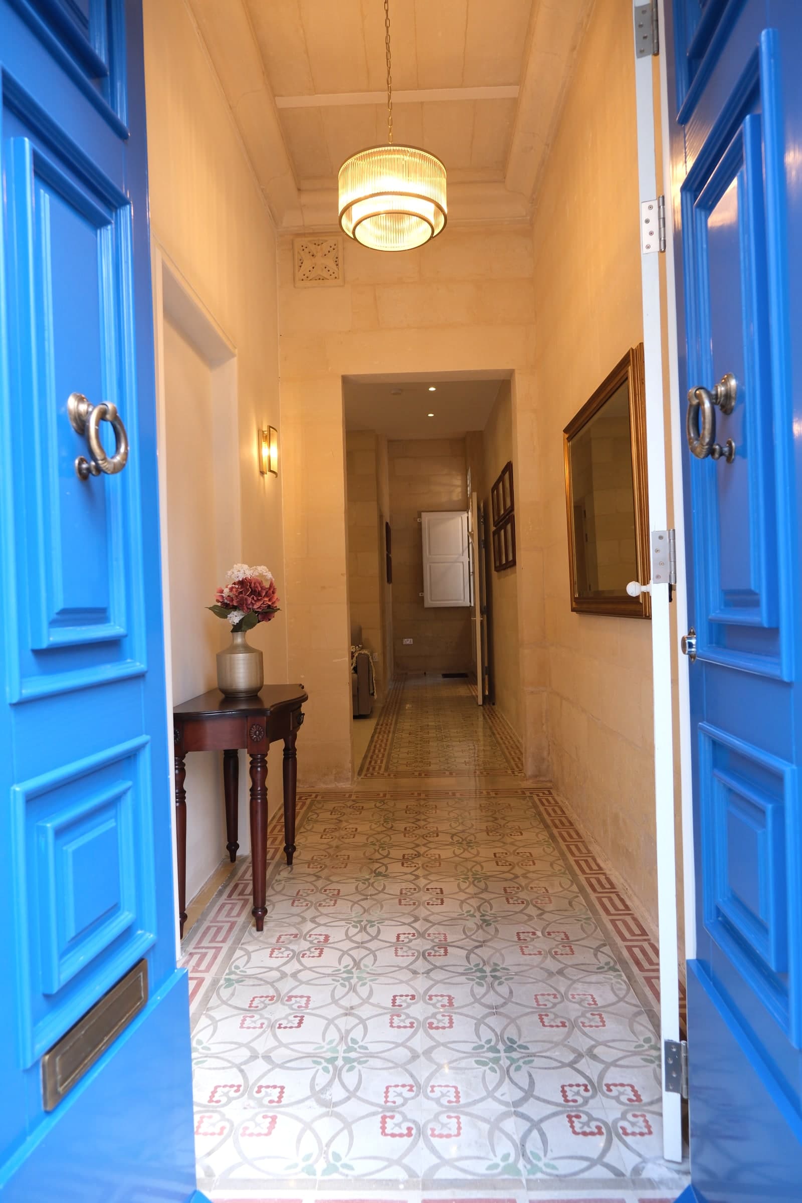 Open blue doors leading into Casa Maria Goretti's restored limestone entrance hallway